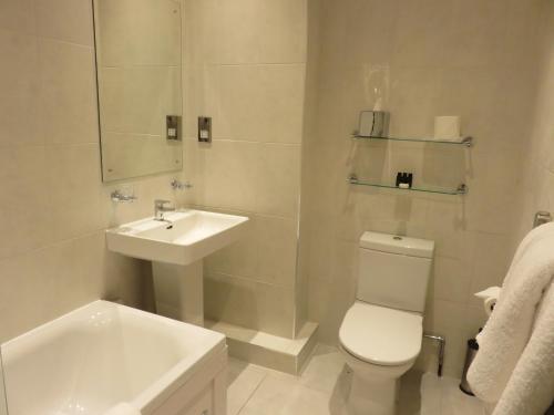 a white bathroom with a sink and a toilet at Belmont Hotel Leicester in Leicester