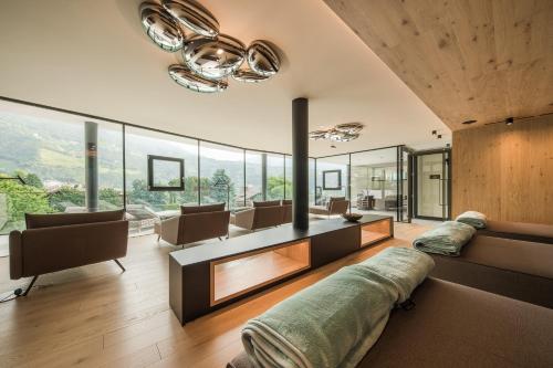 a living room filled with furniture and glass windows at Hotel Das Dorner in Lagundo