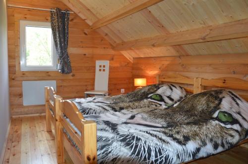 a bed in a cabin with a wooden ceiling at Chalet Les Prés in Neubois