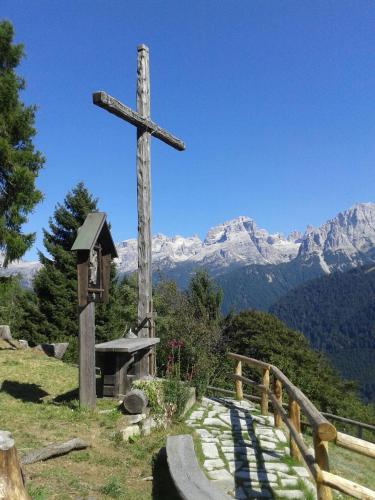 a wooden cross on top of a hill with a mountain at Maso Pin in Madonna di Campiglio
