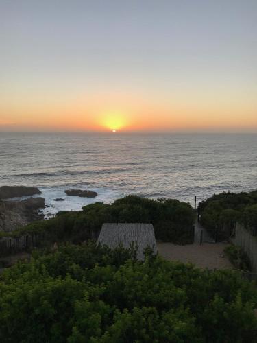 a sunset over the ocean with a house on the beach at Tunquen Magico in Tunquen