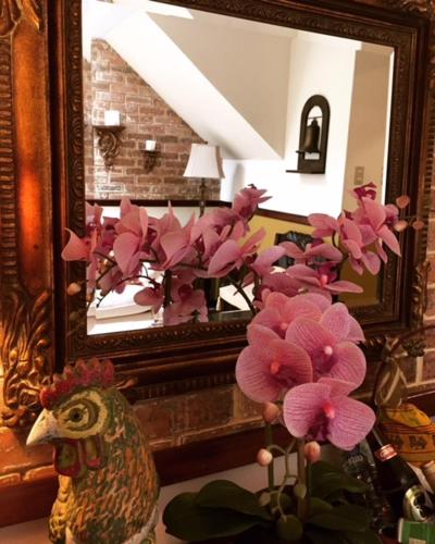 a vase with pink flowers in front of a mirror at Hostal Villa Toscana in Guatemala