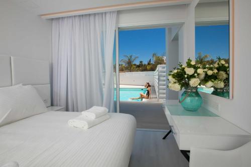 a hotel room with a bed and a window with a pool at Hotel Napa Suites (Adults Only) in Ayia Napa