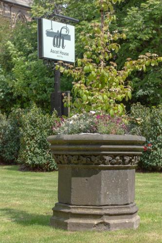 a sign in a park with a planter with flowers at Ascot House in Harrogate