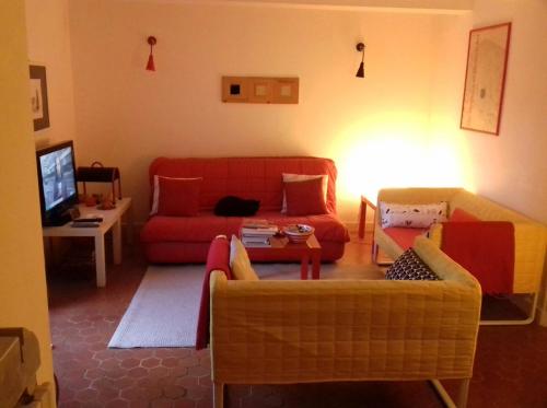a living room with a red couch and a tv at L'Enclos in Lorgues