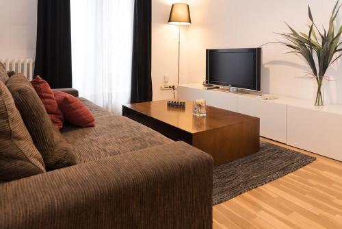 Plaza Mayor - 5 minutos andando في مدريد: غرفة معيشة مع أريكة وتلفزيون بشاشة مسطحة
