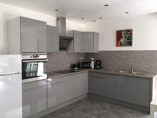 une cuisine avec des armoires blanches et des appareils en acier inoxydable dans l'établissement Appartement confortable et spacieux, à Roisey