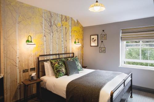 a bedroom with a bed with a tree mural on the wall at Pontcanna Inn in Cardiff