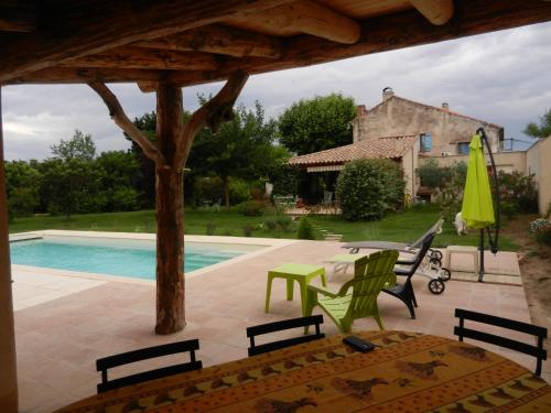 un patio avec une table et des chaises et une piscine dans l'établissement La Fenière aux Hirondelles, à Orange