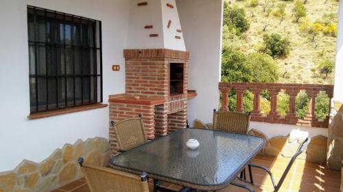 a table and chairs on a balcony with a fireplace at Casa Encina - Encinasola Turismo Rural. in Alora
