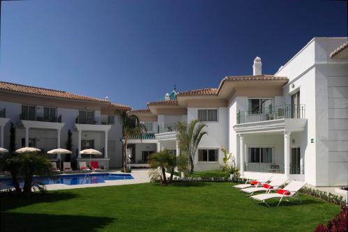 a large white building with lounge chairs and a yard at Apartamentos Marina Turquesa in Nerja