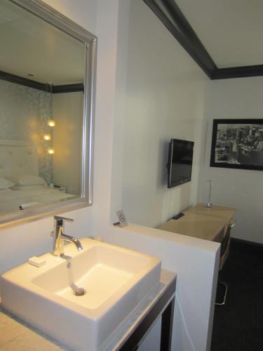 a white bathroom with a sink and a mirror at La Pensione Hotel in San Diego