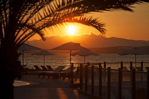 a sunset on the beach with chairs and umbrellas at La Hacienda Bahia Paracas in Paracas