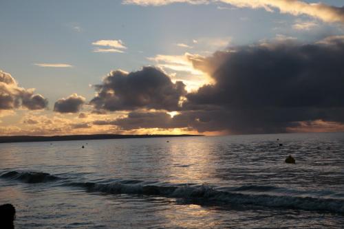 a sunset on the beach with the ocean at FortyOne - Oceanside Retreat Busselton in Busselton