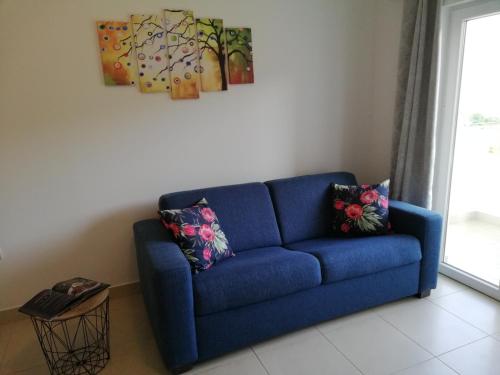 a blue couch in a living room with a painting at Apartments Villa Katija in Drvenik