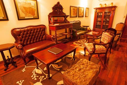a living room with leather furniture and a piano at La Hacienda Bahia Paracas in Paracas