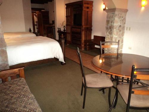 a bedroom with a bed and a table and chairs at Hotel Quinta Mision in Creel