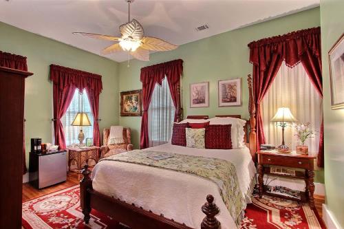 a bedroom with a large bed with red curtains at Green Palm Inn in Savannah