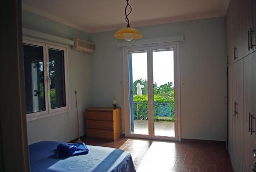 een slaapkamer met een bed en een glazen schuifdeur bij Irimar retreat managed by Hilltop Residences in Mikra Mandinia
