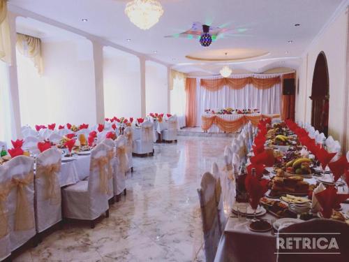 a banquet hall with white tables and white chairs at Hotel Nikoli in Chiatʼura
