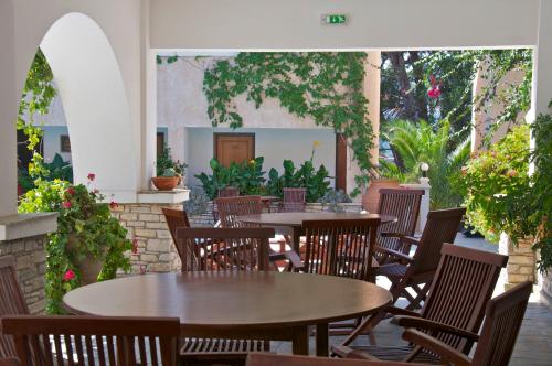 un patio esterno con tavoli, sedie e piante di Ino Village Hotel a Samos