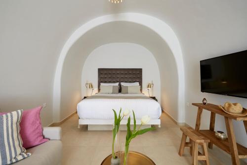 a bedroom with a white bed and a couch at Volcano View by Caldera Collection in Fira