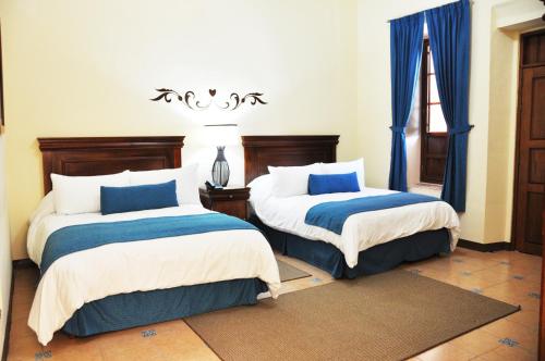 1 dormitorio con 2 camas con sábanas azules y blancas en Gran Casa Sayula Galeria & SPA, en Sayula