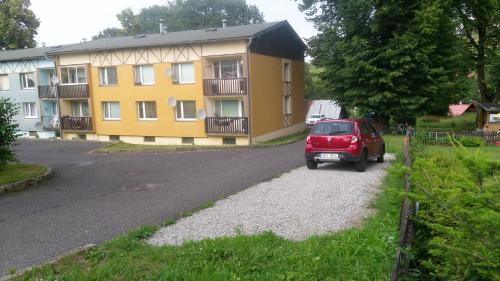 ein rotes Auto, das vor einem Gebäude parkt in der Unterkunft Zelený Apartment in Růžová