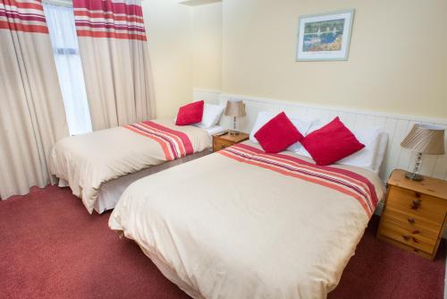 two beds in a hotel room with red pillows at Larkin's Pub, Restaurant, and B&B in Milltown