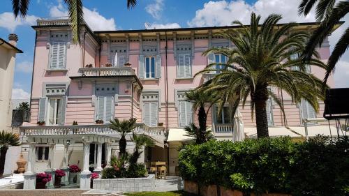 a pink building with palm trees in front of it at Hotel Europa in Lido di Camaiore