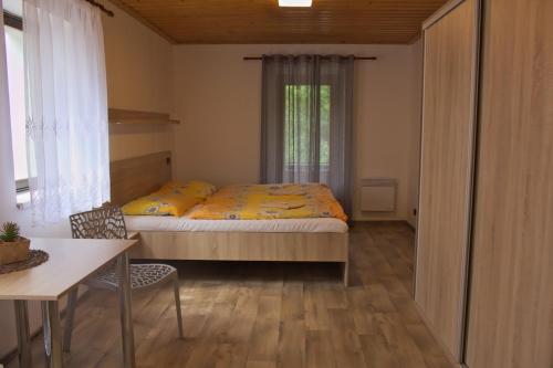 a bedroom with a bed and a table and a window at Penzion Hubert in Mikulov v Krušných Horách