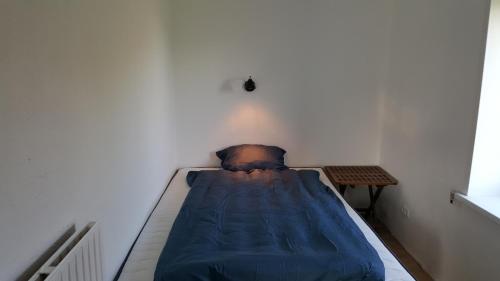 a bed with a blue blanket in a room at Surf And Family Sauna And Spa in Hvide Sande