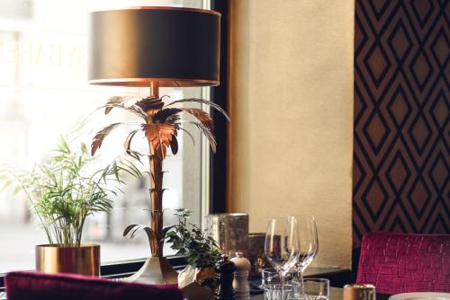 a table with a lamp and wine glasses on it at Statt Hassleholm BW Signature Collection in Hässleholm