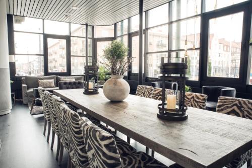 a table with a vase on it in a room with windows at Statt Hassleholm BW Signature Collection in Hässleholm