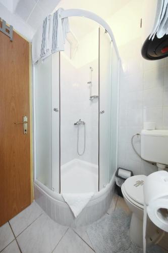 a white bathroom with a shower and a toilet at Apartments Floras in Tkon