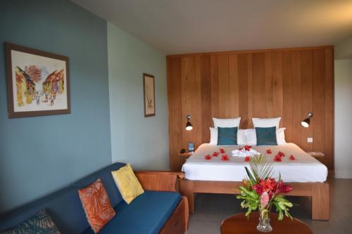 ein Hotelzimmer mit einem Bett und einem blauen Sofa in der Unterkunft Le Panoramic in Les Trois-Îlets
