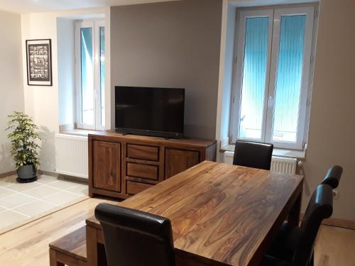 ein Wohnzimmer mit einem Holztisch und einem Flachbild-TV in der Unterkunft Gite d'Emilie - Cahors Centre Ville avec Garage - 3 étoiles in Cahors