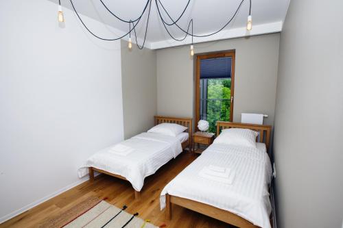 two beds in a room with white walls and wooden floors at Apartament "Park Lotników" in Kraków