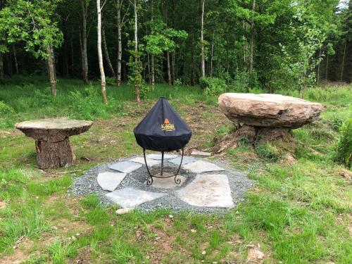 a umbrella sitting on top of two stone benches at Coed y Marchog Woodland Retreat in Hereford