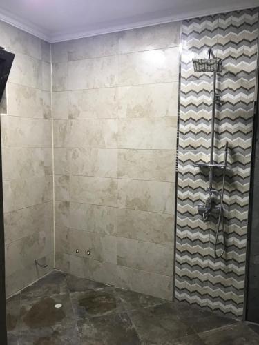 a bathroom with a shower with a stone wall at Beaming_House in Sheki