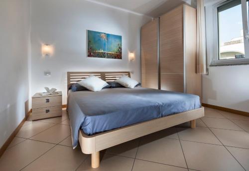 a bedroom with a bed with blue sheets and a window at Appartamenti Aurora in Bibione