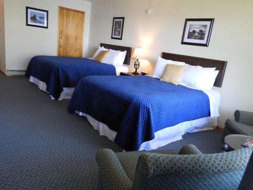 two beds in a hotel room with blue sheets at Admiral Digby Inn Restaurant and Cottages in Digby