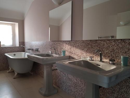 a bathroom with two sinks and a tub and a mirror at Clos Mirabel Manor - Holiday rental in Jurançon