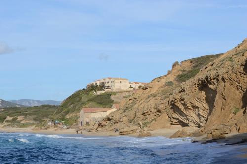 a building on a hill next to a beach at Nel verde del Villaggio - Casetta Celeste in Gonnesa