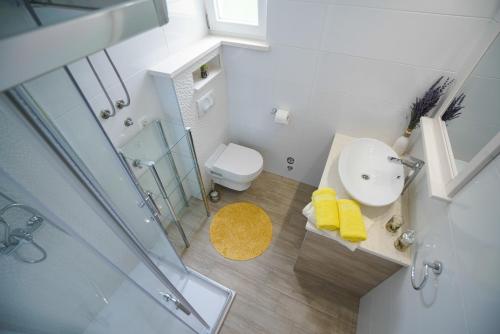 a white bathroom with a sink and a toilet at Apartments Aurora in Zadar