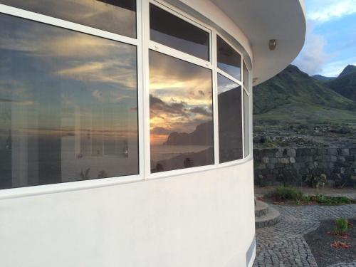 a reflection of a sunset in a window of a house at Questel BronQ in Chã da Igreja