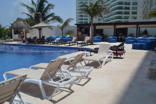 a row of lounge chairs next to a swimming pool at Ocean View Condo in Cancún