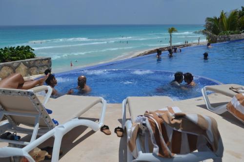 a group of people in a swimming pool next to the beach at Ocean View Condo in Cancún