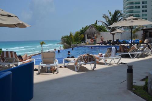 a group of people sitting in chairs at a swimming pool at Ocean View Condo in Cancún