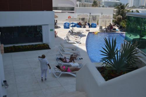 a group of people sitting on lounge chairs next to a pool at Ocean View Condo in Cancún